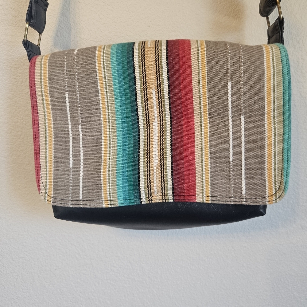black faux leather crossbody bag featuring a colorful striped fabric accent 